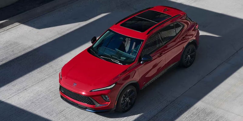 Birds-eye-view shot looking down on a red Buick Envision as it drives headlong across a highway underpass.