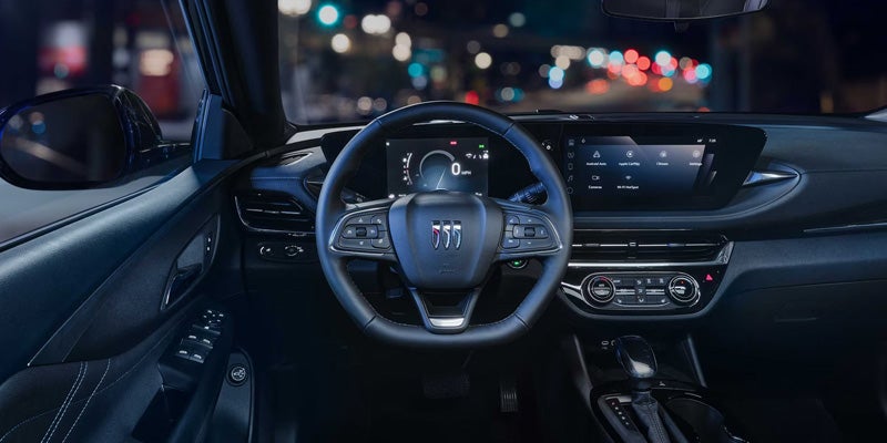 Driver-focused Buick cockpit with a digital instrument cluster and touchscreen infotainment system illuminated at night