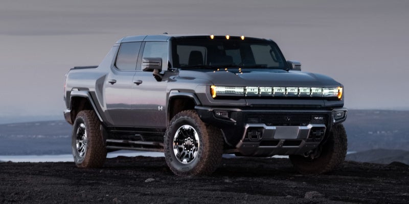 GMC HUMMER EV Pickup parked on rugged terrain, showcasing its off-road capability and electric truck design