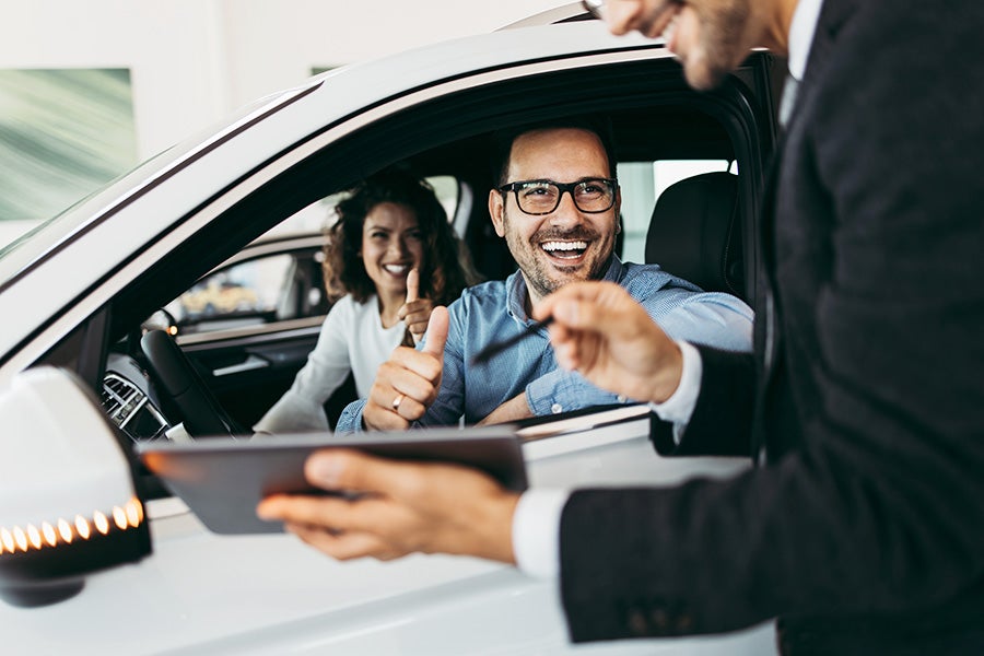Car buyer giving thumbs up during vehicle handover