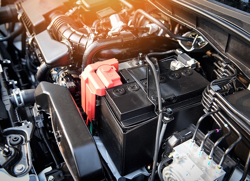 Close-up view of a vehicle battery and engine components inside a car's engine bay