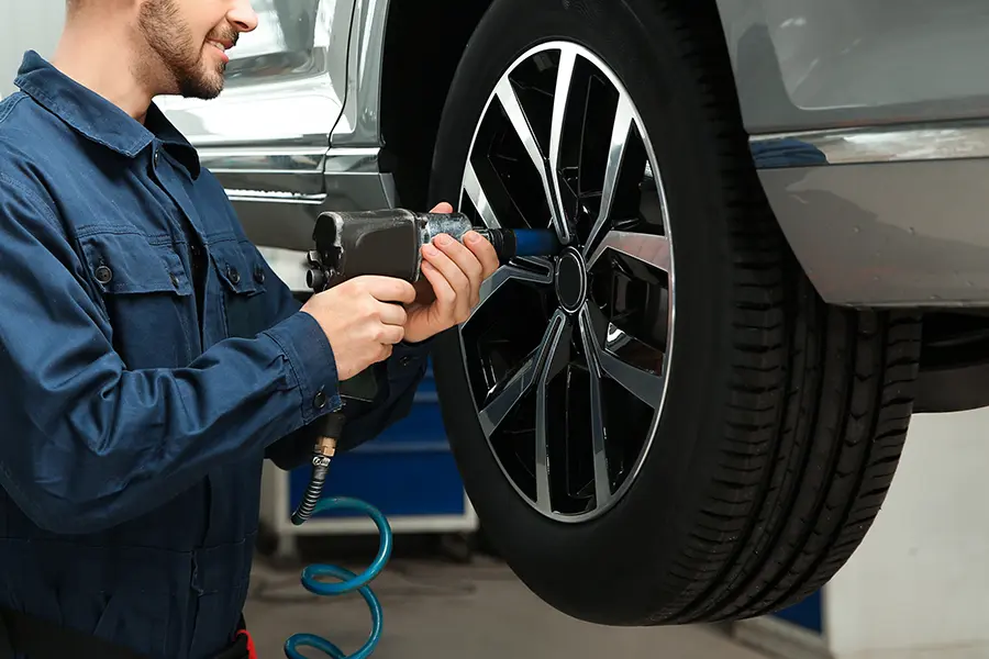 Technician using a pneumatic impact wrench to install or service a vehicle wheel in an automotive repair shop